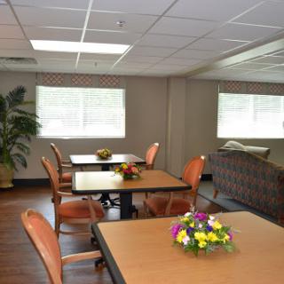 A cozy indoor dining area with tables, chairs, and floral decorations.