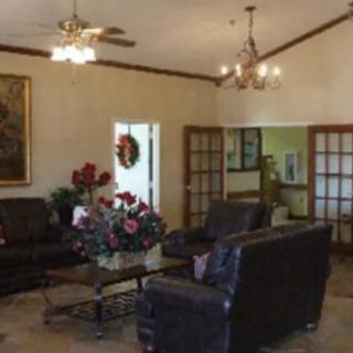 A cozy living room featuring dark leather sofas, a coffee table with a floral centerpiece, and elegant chandeliers.