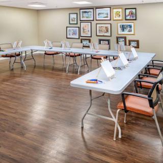 An empty meeting room with U-shaped table arrangement, featuring artwork on the walls and a wooden floor.