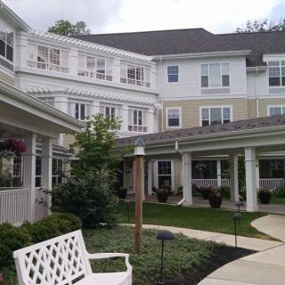 A well-maintained residential building with a spacious courtyard and benches, surrounded by greenery.