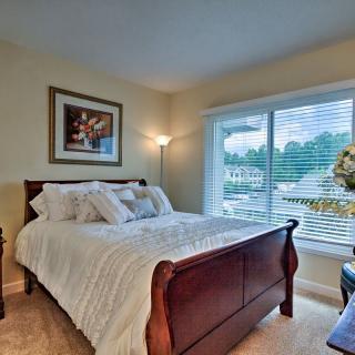 A cozy bedroom with a wooden bed, large window, and decorative elements.