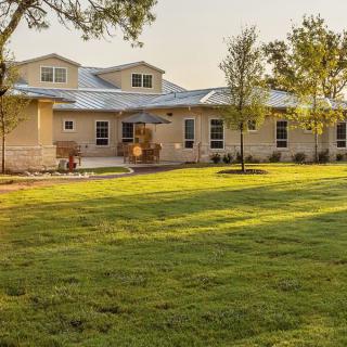 A spacious house with a well-maintained lawn and trees, captured during sunset.