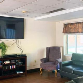 A cozy living room setup with a television mounted on the wall, accompanied by a couch, armchair, and entertainment center.