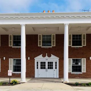 A brick building with large white columns and a central entrance.