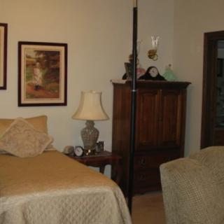A cozy bedroom featuring two beds, a lamp, and framed artwork on the walls.