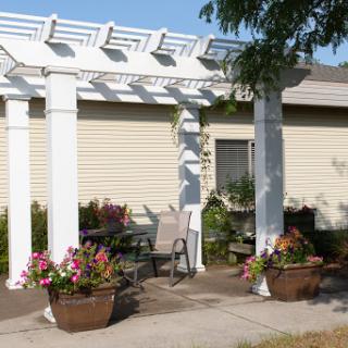A peaceful outdoor setting featuring a white pergola surrounded by colorful flower planters.