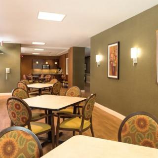 A cozy dining area with tables and chairs arranged neatly, complemented by wall art and warm lighting.
