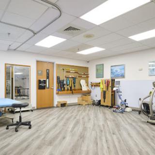 A spacious physical therapy clinic featuring various exercise equipment and treatment areas.