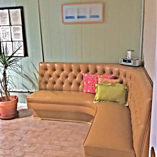 A cozy living room corner featuring a tufted sofa with colorful cushions, a potted plant, and wall art.
