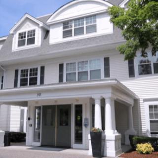 A two-story residential building with a white exterior and multiple windows.