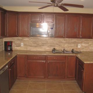 A kitchen with wooden cabinets, a microwave, and a tiled floor.