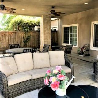 A cozy outdoor patio with wicker furniture and decorative flowers.