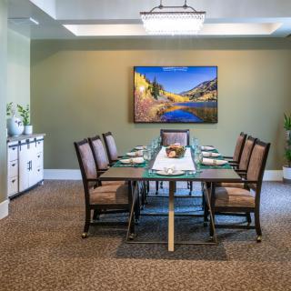 A well-decorated dining room featuring a large table with chairs and a landscape painting on the wall.