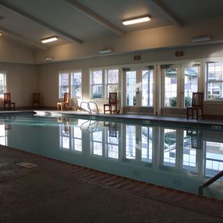 A serene indoor swimming pool with natural light filtering through large windows.