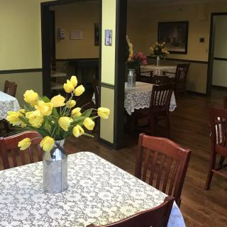 A cozy dining area with tables adorned with yellow tulips in vases, covered with lace tablecloths.