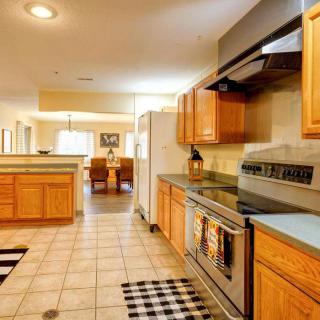 A modern kitchen with wooden cabinets and a tile floor, leading to a dining area.