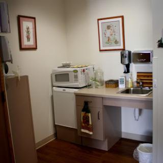 A cozy kitchen space featuring a microwave, sink, and decorative artwork on the walls.