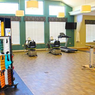A bright and spacious fitness center featuring treadmills, stationary bikes, and various gym equipment.