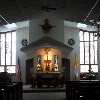 Interior view of a church featuring an altar with a crucifix and stained glass windows.