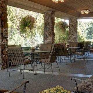 A cozy patio with stone pillars, featuring outdoor seating and hanging plants.