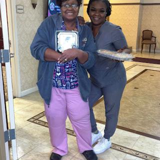 A joyful moment shared between a caregiver and an elderly woman, celebrating together.