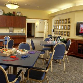 A community room with tables, chairs, and a television for activities.