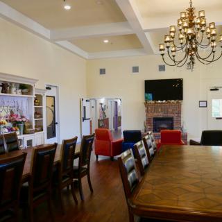 Elegant living and dining area featuring a large table, chandelier, and fireplace.