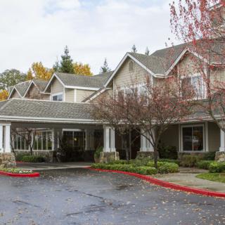 A residential building with a driveway and surrounding trees.
