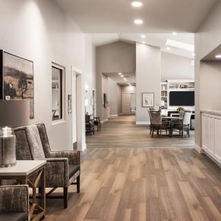 A modern hallway with wooden flooring and stylish furniture, adorned with artwork on the walls.
