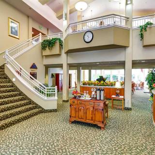 A spacious lobby with a staircase, decorative plants, and comfortable furnishings.
