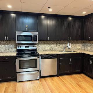 A modern kitchen featuring sleek black cabinets, stainless steel appliances, and a stylish granite countertop.