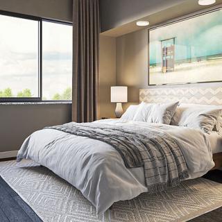 A modern and cozy bedroom with a neatly made bed, stylish bedside lamp, and large window.
