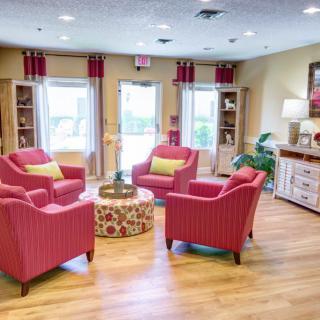 A bright and cozy living room with modern decor, featuring red armchairs and a central coffee table.