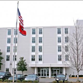 A multi-story office building with cars parked in front and flags displayed.