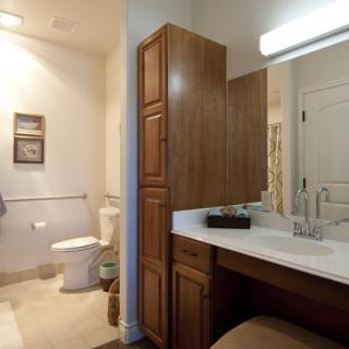 A modern bathroom featuring a wooden cabinet, sink with a mirror, and a toilet.