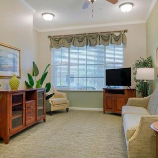 A cozy living room with a sofa, armchair, TV, and large window.