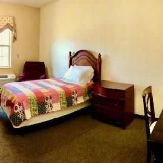 A cozy bedroom with a single bed, wooden furniture, and a colorful quilt.