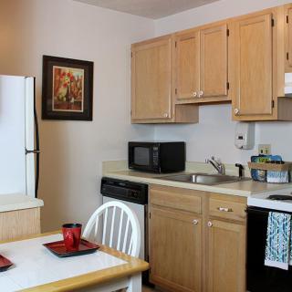 Cozy kitchen with wooden cabinets, a microwave, and a small dining area.