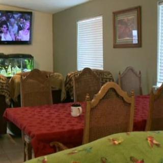 A cozy dining room with tables set for service, featuring a wall-mounted television and an aquarium.