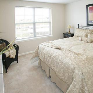 A cozy bedroom with a neatly made bed and natural light coming through the window.