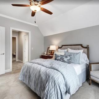 A cozy bedroom with a bed, nightstand, and ceiling fan.