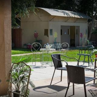 A sunny outdoor patio with tables and chairs set on a lawn.