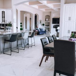 A modern and spacious open-plan kitchen and dining area featuring sleek seating and a marble floor.