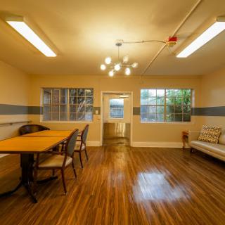 A cozy and well-lit interior room featuring a wooden table, chairs, and a comfortable seating area.