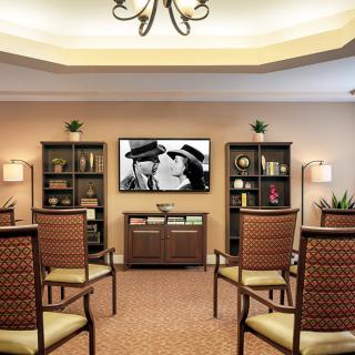 A cozy living room with arranged seating, a television displaying a classic movie, and bookshelves lining the walls.
