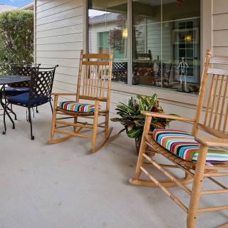 A cozy porch with wooden rocking chairs and a small table set, perfect for relaxing outdoors.