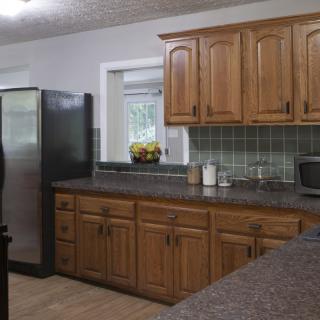 A modern kitchen with wooden cabinets and a black refrigerator.