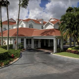A picturesque house with red roofs and a manicured driveway surrounded by lush greenery.