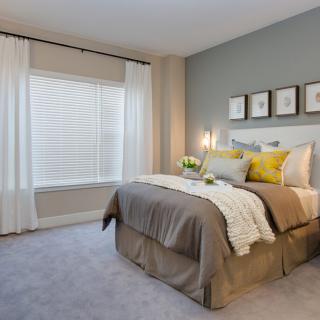 A modern bedroom with neutral tones and cozy decor.