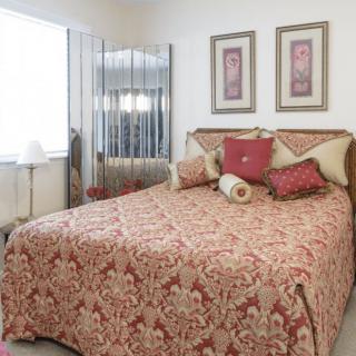 A cozy bedroom with a patterned bedspread, decorative pillows, and artwork on the walls.